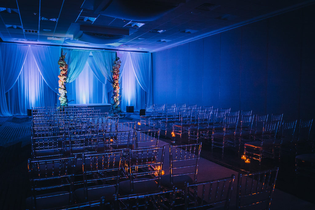 Elegant, Modern, Contemporary Wedding Ceremony Decor, Clear Acrylic Ghost Chiavari Chairs, Blue Uplighting, White Draping and Tall Large Floral Pillars | Tampa Bay Boutique Hotel Wedding Venue Hotel Alba | Wedding Planner Special Moments Event Planning | Wedding Rentals and Chair Decor Gabro Event Services | Styled Shoot