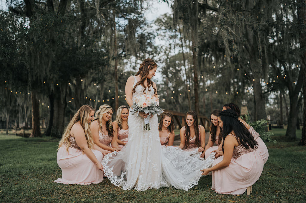 INSTAGRAM Tampa Rustic Chic Bridesmaids Wearing Matching Blush Pink Sparkle Glitter Dresses Holding Bride's Lace and V Neckline Wedding Dress Train with Blush Pink and White Roses with Dusty Miller Leaves | Parrish Wedding Venue Rafter J Ranch