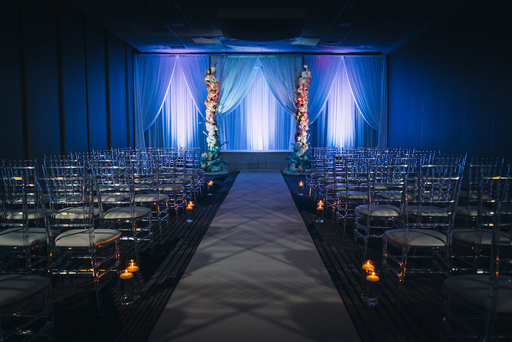 Elegant, Modern, Contemporary Wedding Ceremony Decor, Clear Acrylic Ghost Chiavari Chairs, Blue Uplighting, White Draping and Tall Large Floral Pillars | Tampa Bay Boutique Hotel Wedding Venue Hotel Alba | Wedding Planner Special Moments Event Planning | Wedding Rentals and Chair Decor Gabro Event Services | Styled Shoot