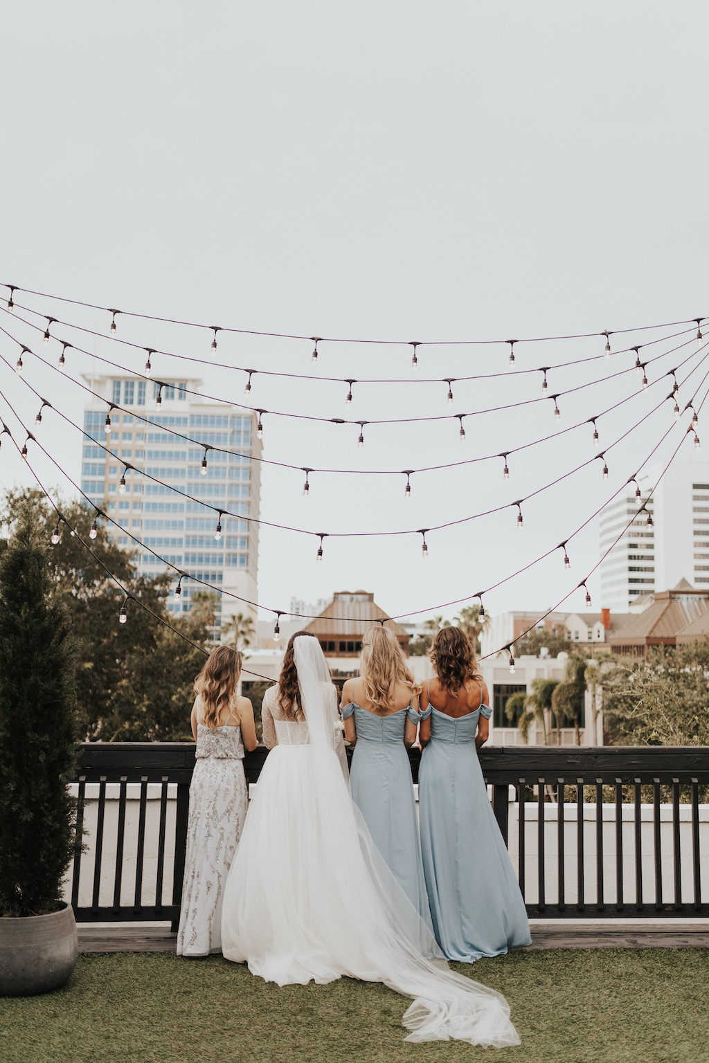 Bride in Vera Wang High Neck Lace and Tulle Corset Bodice Long Sleeve Wedding Dress, Bridesmaids in Dusty Blue Off the Shoulder Matching Dresses, Rooftop Wedding Portrait | St. Pete Rooftop Wedding Venue Station House
