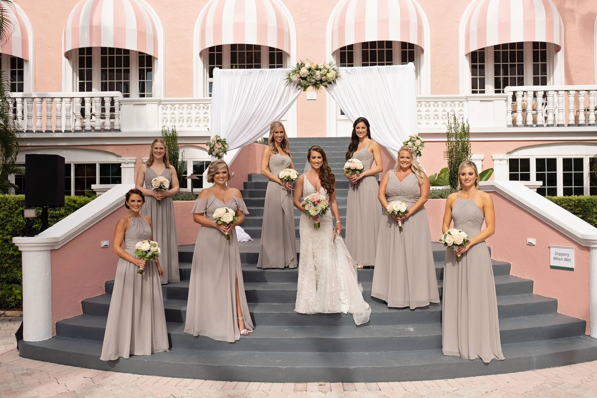 Florida Bridal Party, Bride and Bridesmaids holding Romantic White and Pink Floral Bouquet, Bride Wearing Hayley Paige Lace Overlay Fit and Flare Wedding Dress, Bridesmaids Wearing Long Beige Azazie Dresses | St. Pete Beach Historic Wedding Venue The Don CeSar Hotel