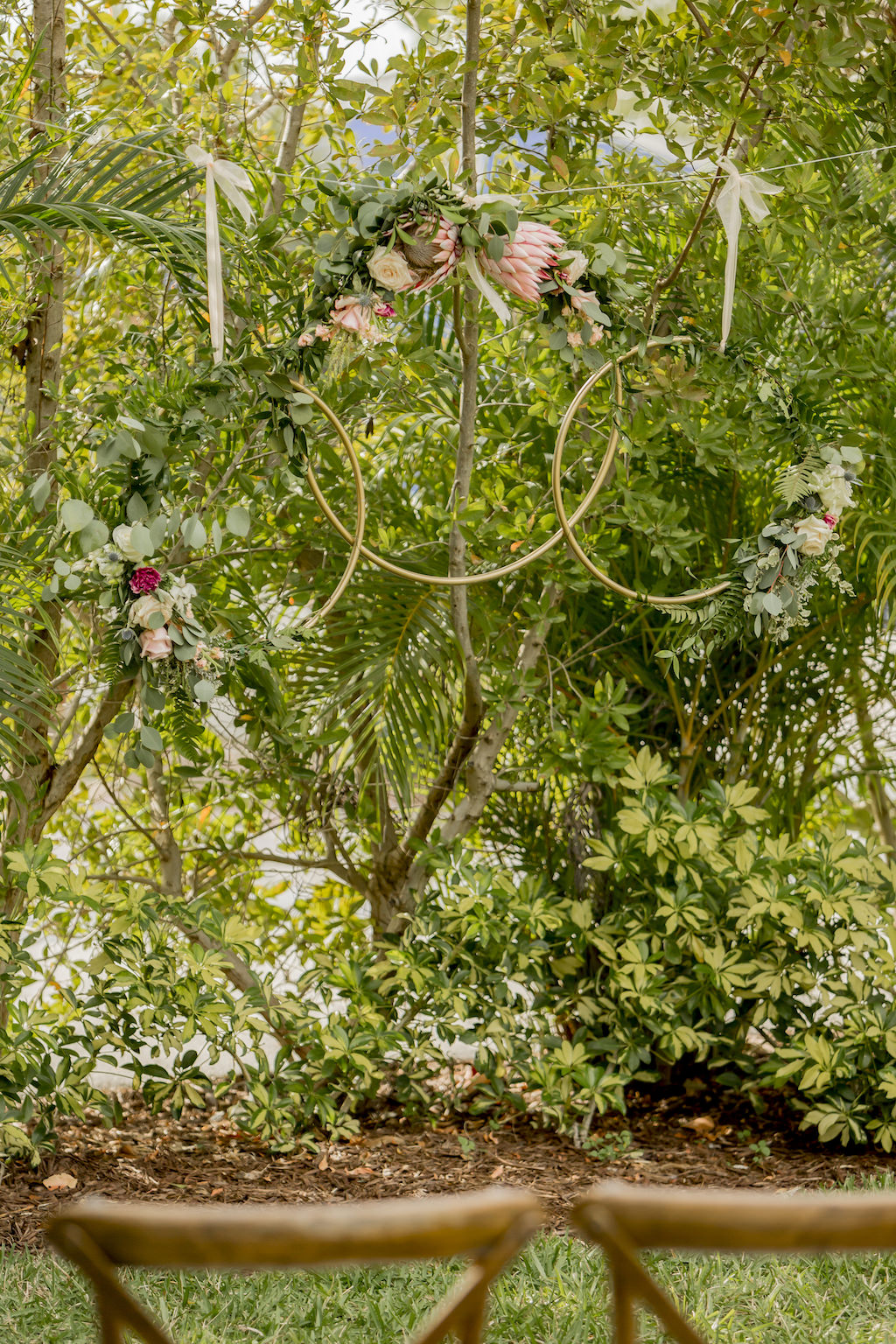 St. Pete Garden Wedding Ceremony Decor, Three Hanging Golden Hoops with King Proteas, Ivory, Red and Blush Pink Roses and Greenery Floral Arrangements