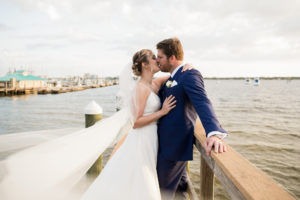 Classic Romantic Waterfront Wedding Portrait with Bride's Veil Blowing in the Wind