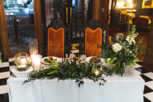 Romantic Modern New Years Eve Wedding Reception Decor, Sweetheart Table with White Linen, Greenery and White Roses Floral Arrangements, Gold Geometric Candle Holders, Antique Wood and Orange Velvet Chairs