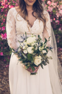 Tampa Bay Bride in Boho Inspired Flowy, Lace and Illusion V Neckline Long Sleeve Wedding Dress Holding Rustic Chic Floral Bouquet with White and Ivory Roses, Blue Thistle, Eucalyptus Leaves, Silver Sage Flowers and Gray Accents | Tampa Bay Wedding Photographer Luxe Light Images