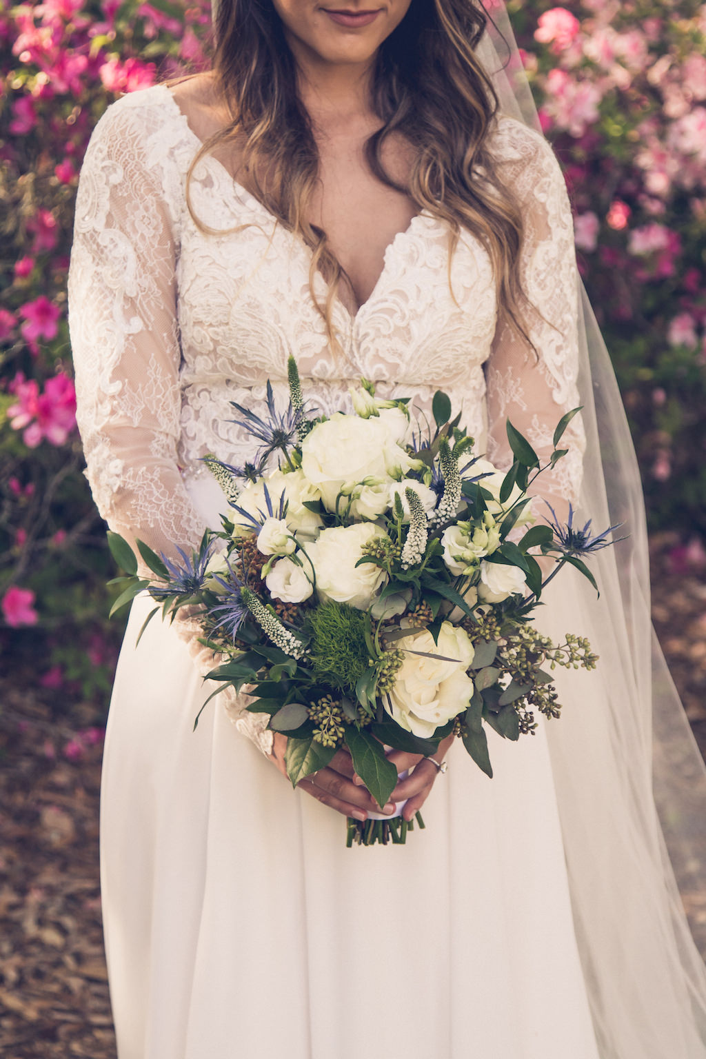 Tampa Bay Bride in Boho Inspired Flowy, Lace and Illusion V Neckline Long Sleeve Wedding Dress Holding Rustic Chic Floral Bouquet with White and Ivory Roses, Blue Thistle, Eucalyptus Leaves, Silver Sage Flowers and Gray Accents | Tampa Bay Wedding Photographer Luxe Light Images