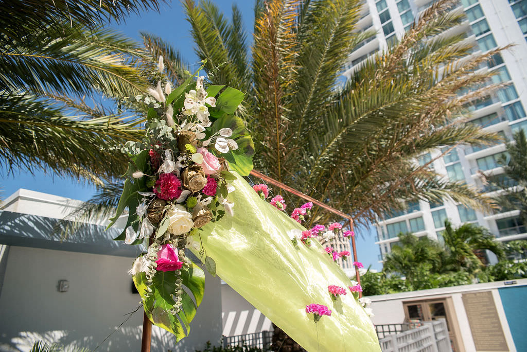 Colorful, Tropical Wedding Ceremony Decor, Copper Arch with Lime Green Draping, Fuschia Pink Carnations, Ivory and Pink Roses, White Orchids, Monstera Palm Leaves Floral Arrangement | Tampa Bay Wedding Photographer Kristen Marie Photography | Hotel Wedding Venue Hyatt Place Downtown St. Pete | Wedding Florist Brides N Blooms | Outside the Box Event Rentals