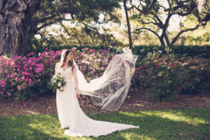 Florida Bride in Boho Inspired Lace and Illusion Long Sleeve Wedding Dress Holding Rustic Chic Floral Bouquet with Cathedral Long Veil Blowing In The Wind | Tampa Bay Wedding Photographer Luxe Light Images
