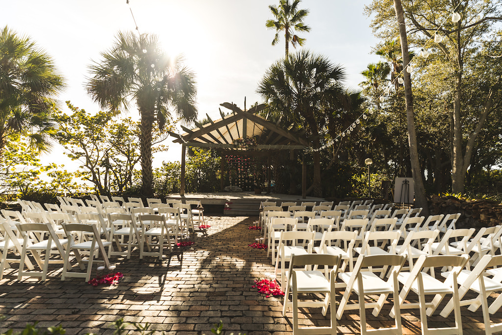 Tampa Bay Outdoor Courtyard Boho Chic Wedding Ceremony Decor, White Folding Chairs, Pink Flower Petals, Hanging String Lights, Gazebo