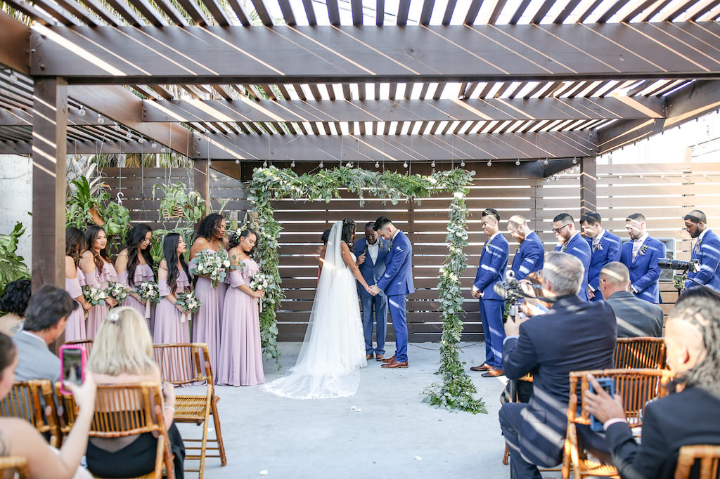 Industrial Boho Chic Wedding Ceremony Bride and Groom Exchanging Vows Wedding Portrait Under Courtyard Pergola and Greenery Adorned Arch | Tampa Bay Wedding Photographer Lifelong Photography Studio | Wedding Planner Special Moments Event Planning | Unique Wedding Ceremony Venue Fancy Free Nursery