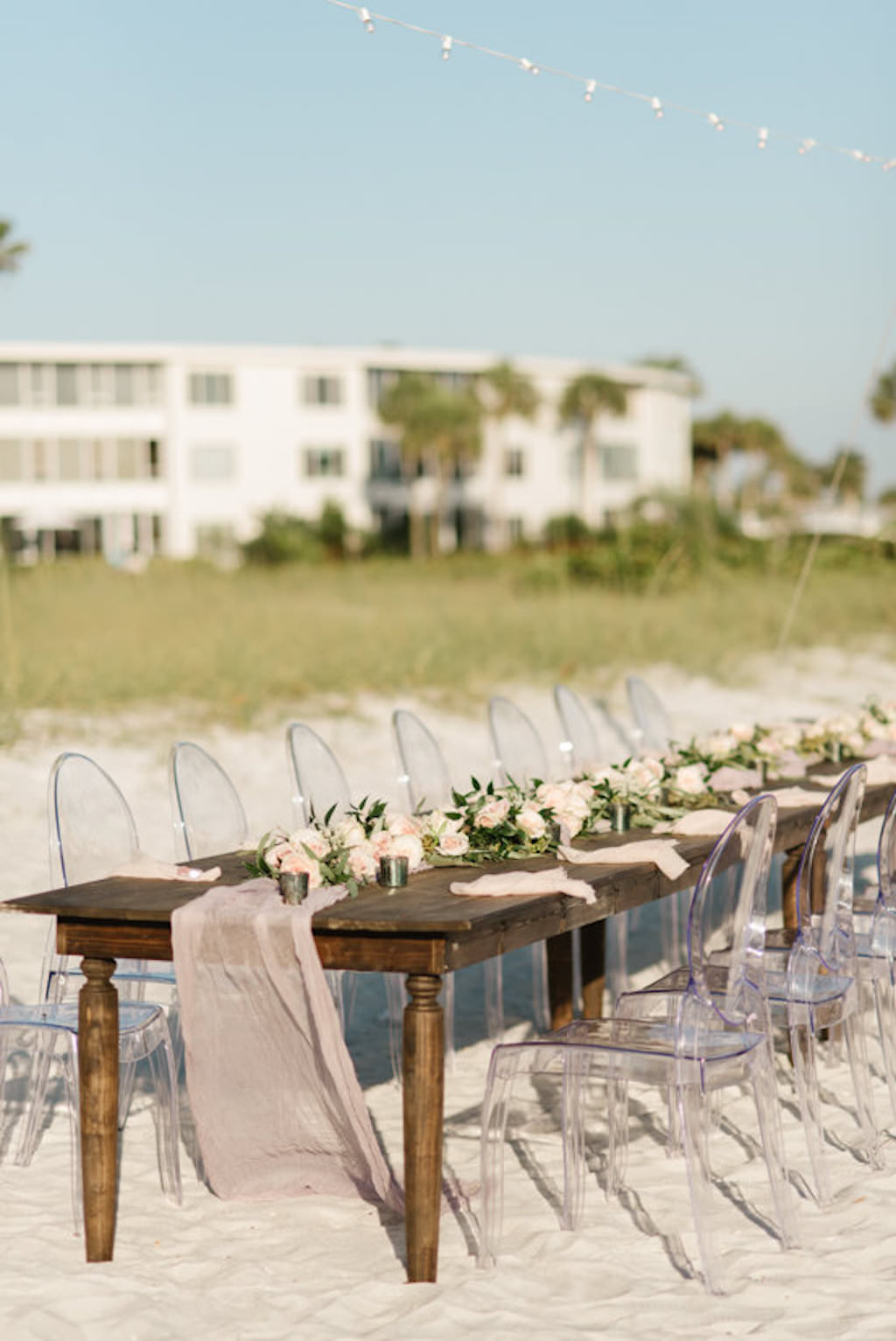 Outdoor Beachfront Wedding Reception with Long Wooden Feasting Table and Ghost Chairs | Resort at Longboat Key Club Sarasota Area Wedding Venue