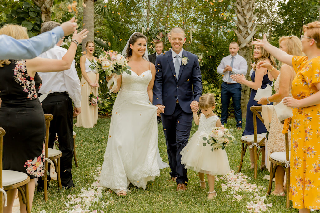 St. Pete Bride, Groom, and Daughter as Flower Girl Exiting Wedding Ceremony Portrait with Flower Confetti Petals Being Thrown