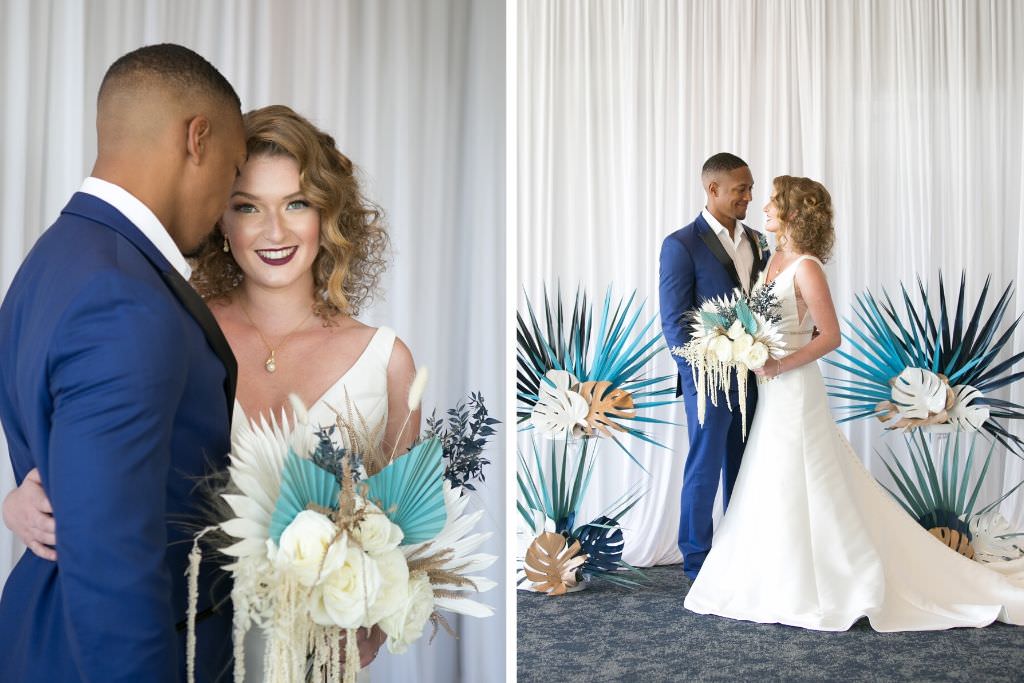 Romantic Wedding Portrait, Bride with Short Loose Waves Wearing Classic A-Line V Neck Wedding Dress Holding Whimsical Unique White Roses, Greenery Floral Bridal Bouquet, Groom in Blue Suit with Black Collar Trim, Gold, White and Green Palm Tree and Monstera Leaves Arrangements with White Linen Draping Backdrop | Tampa Wedding Venue Centre Club | Wedding Planner and Florist John Campbell Weddings | Wedding Hair and Makeup Michele Renee the Studio | Wedding Bridal Attire Truly Forever Bridal | Wedding Draping Gabro Event Services | Wedding Photographer Carrie Wildes Photography
