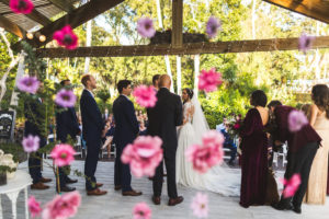 Whimsical Boho Chic Wedding Ceremony Bride and Groom Exchanging Vows and Pink and Purple Hanging Flowers at Gazebo