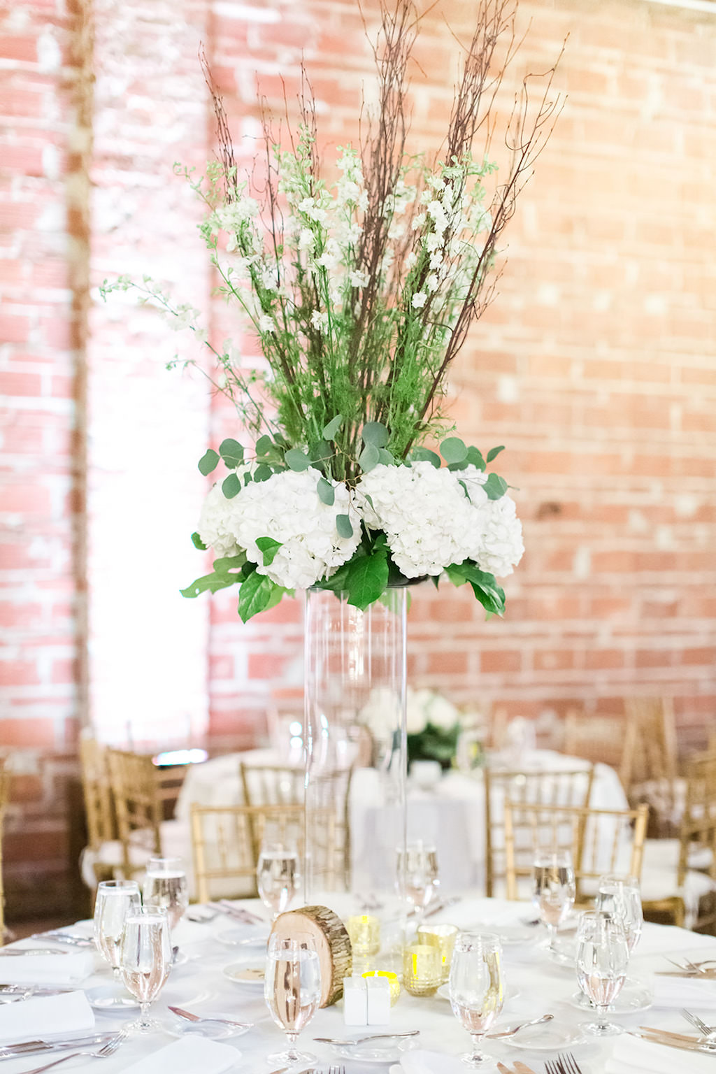 Rustic Chic Wedding Decor, White Hydrangeas, Greenery and Texture, Natural Element Wood Table Number, Gold Chiavari Chairs, Against Exposed Red Brick Wall | Florida Historic Wedding Venue NOVA 535 | Downtown St. Pete Wedding Photographers Shauna and Jordon Photography
