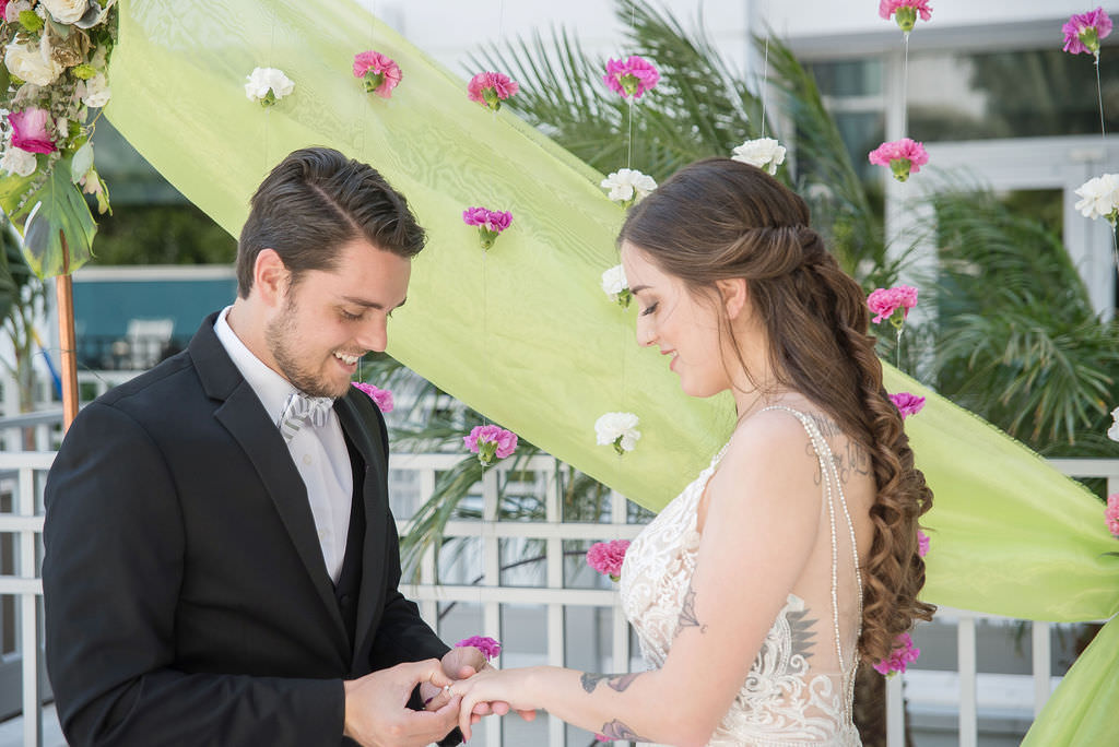 Modern Bride in Lace and Illusion Low Open Back with Rhinestone Lining Spaghetti Strap Wedding Dress and Groom in Black Tuxedo Wedding Portrait, Colorful Tropical Wedding Ceremony Decor, Copper Arch, Fuchsia Pink and White Hanging Carnations, Lime Green Draping | Tampa Bay Wedding Photographer Kristen Marie Photography | Hotel Wedding Venue Hyatt Place Downtown St. Pete | Wedding Florist Brides N Blooms | Wedding Attire Nikki's Glitz and Glam Boutique | Outside the Box Event Rentals | Wedding Hair and Makeup LDM Beauty Group