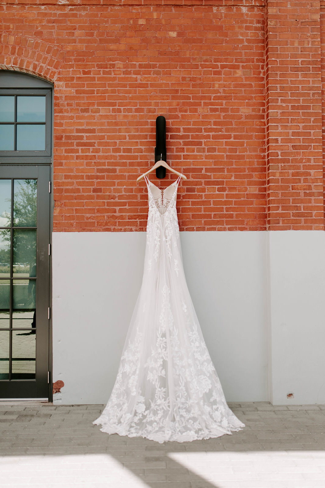 Boho Martina Liana Whimsical Lace and Tulle Open V Back A-Line Wedding Dress Hanging Outside Red Brick Industrial Building Tampa Wedding Venue Armature Works