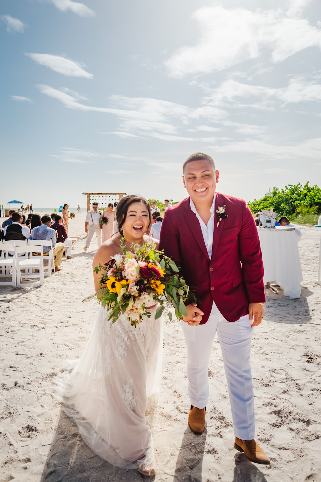 Tampa Bay Bride and Groom Beachfront Happy Wedding Ceremony Recessional Exit Portrait, Bride Holding Tropical Organic Yellow Sunflower, Red, Pink and Purple Flowers and Greenery Bridal Bouquet
