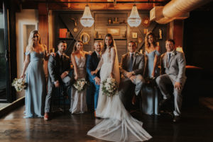 Romantic Bride in Vera Wang High-Neck Lace and Tulle Corset Bodice Long Sleeve Wedding Dress and Full Length Veil, Groom, Bridesmaids in Dusty Blue Dresses, Groomsmen in Gray Suits Wedding Party Portrait | St. Petersburg Wedding Venue Station House