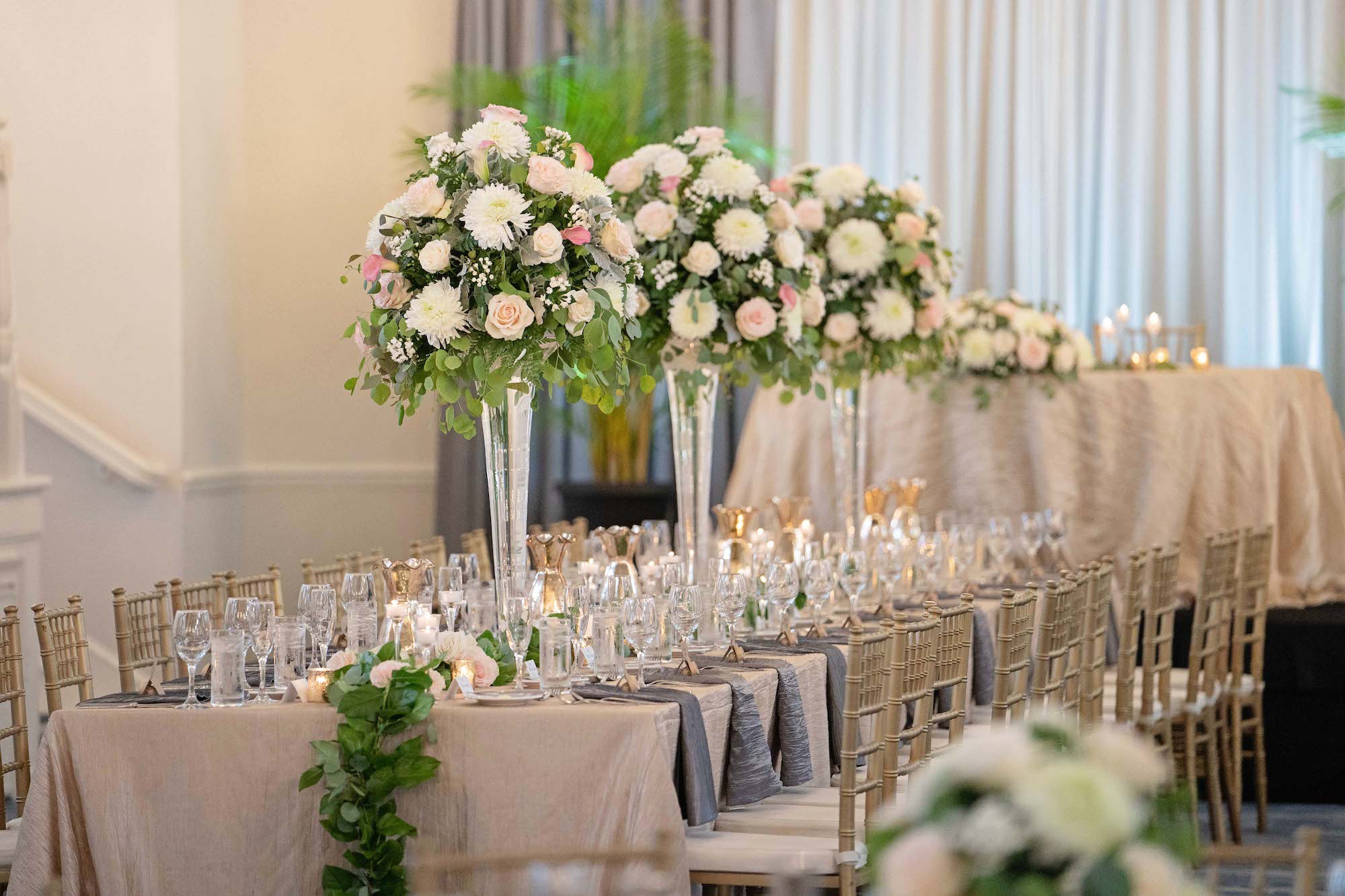 Elegant Summer Wedding Reception Decor in Ballroom, Gold Chiavari Chairs with Wedding Party Head Table, with Silver and Gold Linens, Palm Leaf Decor, Towering Floral Centerpieces with White and Blush Pink Flowers | Tampa Bay Historic Wedding Venue The Don CeSar on St. Pete Beach
