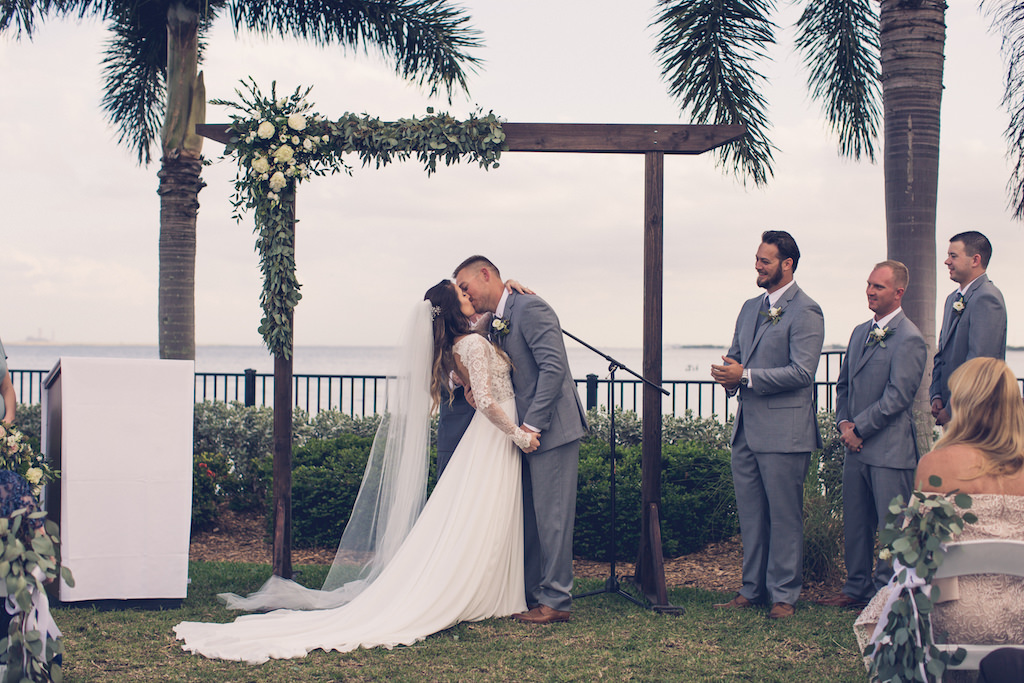 Tampa Bay Bride and Groom Kiss at the Altar in Outdoor Waterfront Rustic Wedding Ceremony | Florida Wedding Photographer Luxe Light Images | Wedding Venue Tampa Yacht and Country Club