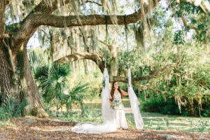 Whimsical Bride on Whimsical Swing Hanging from Oak Trees with White Linens Outdoors in Enchanted Tampa Bay Garden | Romantic Plant City Wedding Venue Florida Rustic Barn Weddings