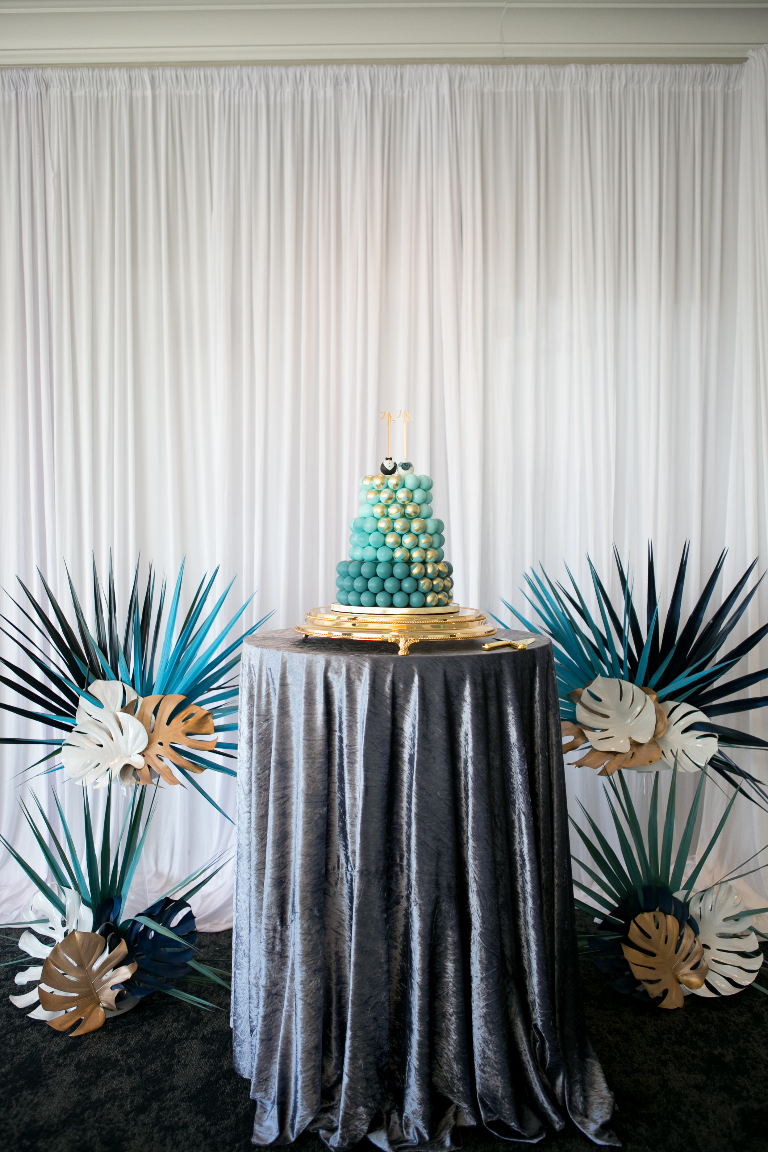 Unique Whimsical Ombre Blue with Gold Accent Cake Pop Three Tier Wedding Cake on Table with Midnight Blue Velvet Linen, White, Gold and Blue Monstera Palm Tree Leaves | Wedding Planner and Florist John Campbell Weddings | Tampa Wedding Venue Centre Club | Wedding Linen Rentals Kate Ryan Event Rentals | Tampa Wedding Cake Pop Cake Sweetly Dipped Confections