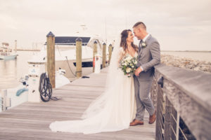 Boho Elegant Inspired South Tampa Bride and Groom on Pier at Sunset Holding Rustic Chic Wedding Floral Bouquet with White Roses and Greenery | Tampa Bay Wedding Photographer Luxe Light Photography | Florida Wedding Photographer Luxe Light Images | Wedding Venue Tampa Yacht and Country Club