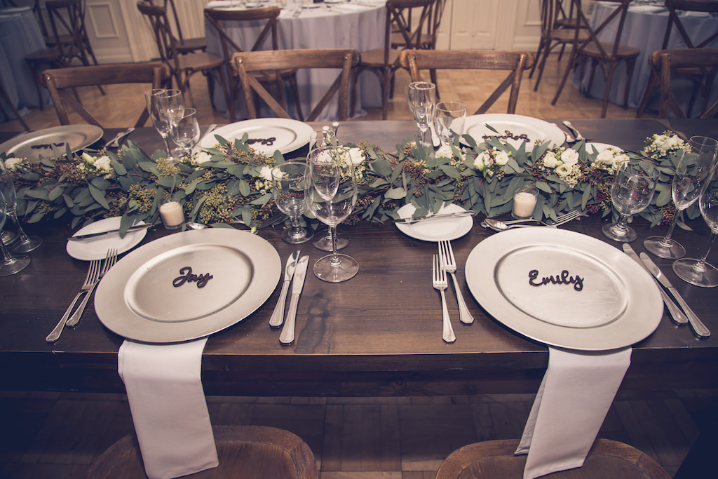 Rustic Chic Inspired Wedding Reception Decor, Boho Elegant Silver Chargers with Custom Laser Cut Name, Wooden Feasting Table, Green Eucalyptus Leaf Garland Table Runner, Wood Cross-back Chairs | Florida Luxury Wedding Photographer Luxe Light Images