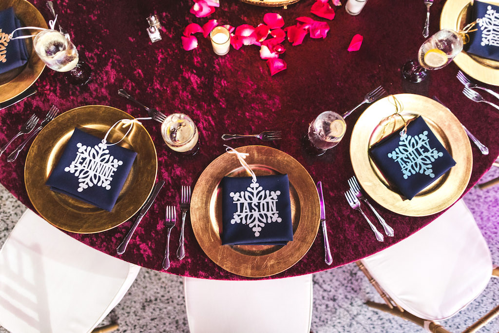INSTAGRAM Boho Chic Wedding Reception Decor, Round Table with Merlot Red Linen, Gold Chargers, Custom Silver Snowflake Place Cards and Pink Flower Petals | Tampa Bay Wedding Catering Company Olympia Catering & Events