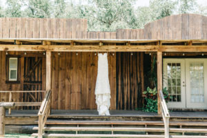 Romantic Lace Wedding Dress Hanging from Antique Wood Porch | Tampa Bay Private Outdoor Wedding Venue Florida Rustic Barn Weddings