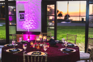 Boho Chic Wedding Reception Decor, Round Table with Merlot Linen, Gold Chargers, Glass Hurricane Floating Candles, Pink Uplighting | Tampa Bay Wedding Catering Company Olympia Catering & Events | St. Petersburg Wedding Reception Venue Admiral Farragut Academy