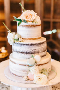 Rustic Inspired Dessert Table with Three Tier Semi Frosted Naked Wedding Cake, Macaroons Garnished with Read Blush Pink and Ivory Roses | Tampa Bay Wedding Venue Florida Rustic Barn Weddings