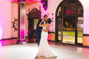 Romantic Bride and Groom First Dance Kiss Wedding Portrait with Pink Uplighting | Tampa Bay Wedding DJ Grant Hemond & Associates | St. Petersburg Wedding Reception Venue Admiral Farragut Academy