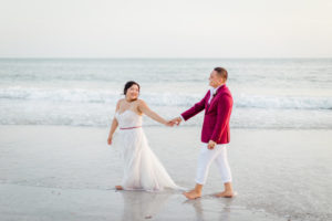 Waterfront Bride in Flowy Strapless Lace and Tulle Wedding and Dress, Groom in Red Suit Jacket and White Dress Pants St. Pete Beach Wedding Portrait