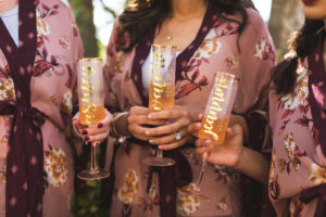 Tampa Bride and Bridesmaids with Personalized Gold Font Champagne Flutes Wearing Mauve Floral Robes