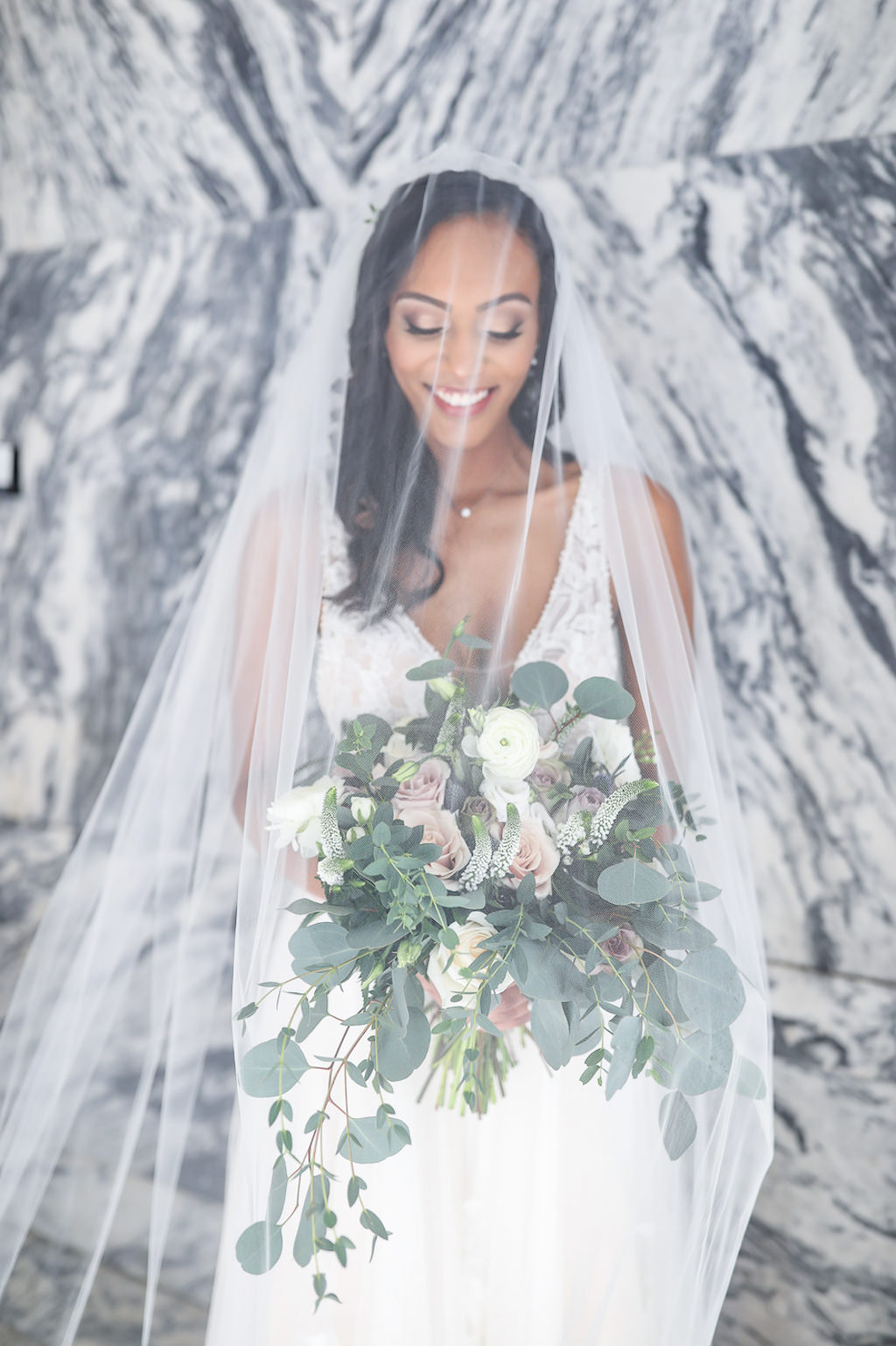 Florida Boho Chic Bride in Plunging V Neckline Lace and Tulle Skirt Wedding Dress with Cathedral Length Veil Over Face Holding Organic Silver Dollar Eucalyptus, White and Blush Pink Rose Floral Bridal Bouquet Wedding Portrait | Tampa Bay Wedding Photographer Lifelong Photography Studio | Wedding Hair and Makeup Femme Akoi Beauty Studio