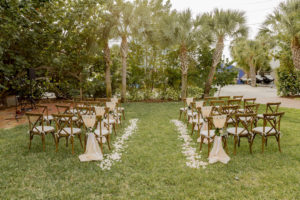 St. Pete Garden Inspired Wedding Ceremony Decor, Wooden Cross-back Chairs, Flower Petal Aisle Runner, Blush Pink Chair Sashes with Greenery Tie
