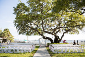 Simple Waterfront Wedding Ceremony Decor, White Folding Chairs and White Altar with Large Oak Tree and Lanterns | Tampa Wedding Venue Palmetto Riverside Bed and Breakfast | Sarasota Wedding Planner Coastal Coordinating