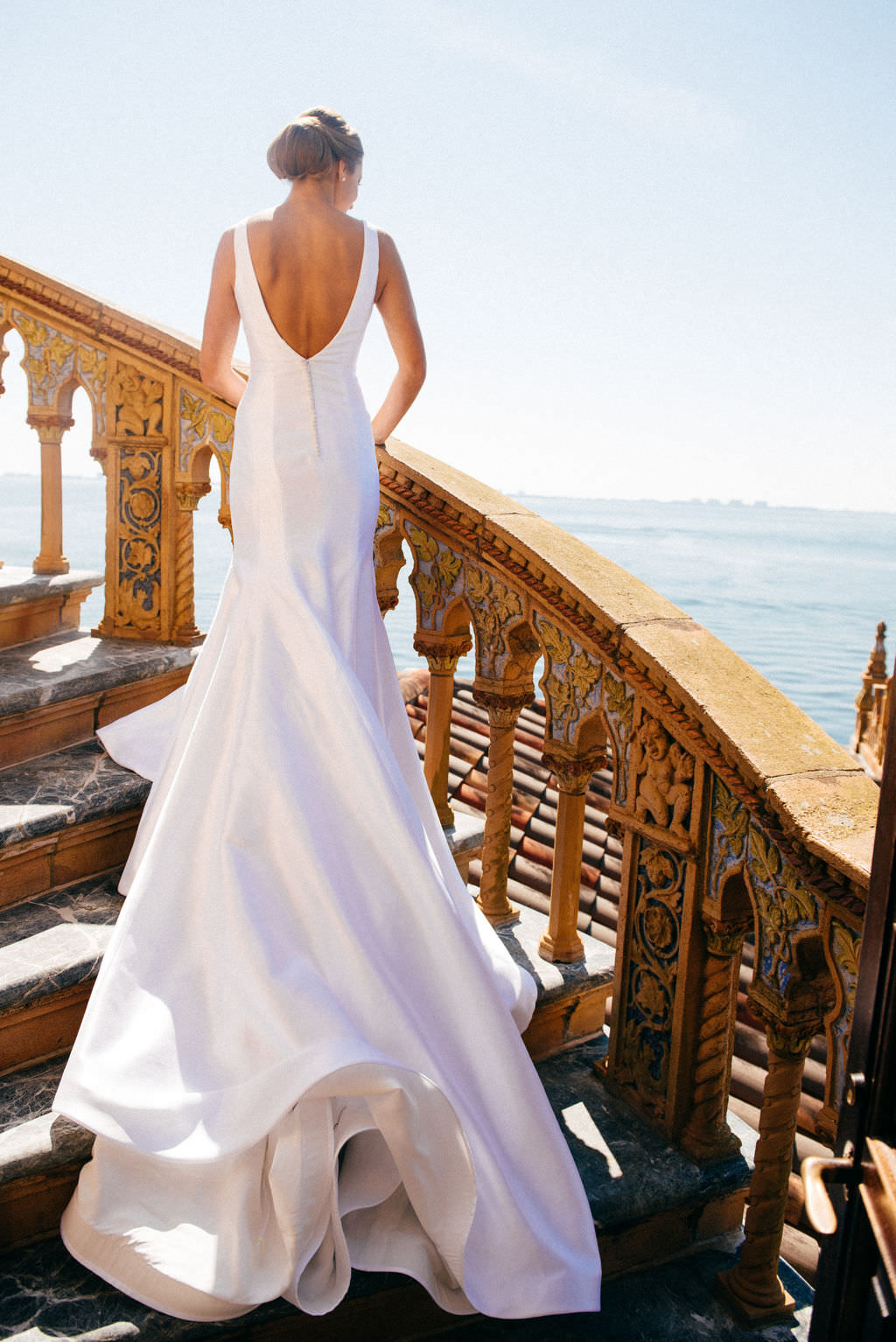 Bride in Classic Silhouette Open Back Wedding Dress on Staircase at Waterfront Sarasota Wedding Venue Ca d’Zan at The Ringling Museum | Tampa Bay Wedding Hair and Makeup Femme Akoi Beauty Studio