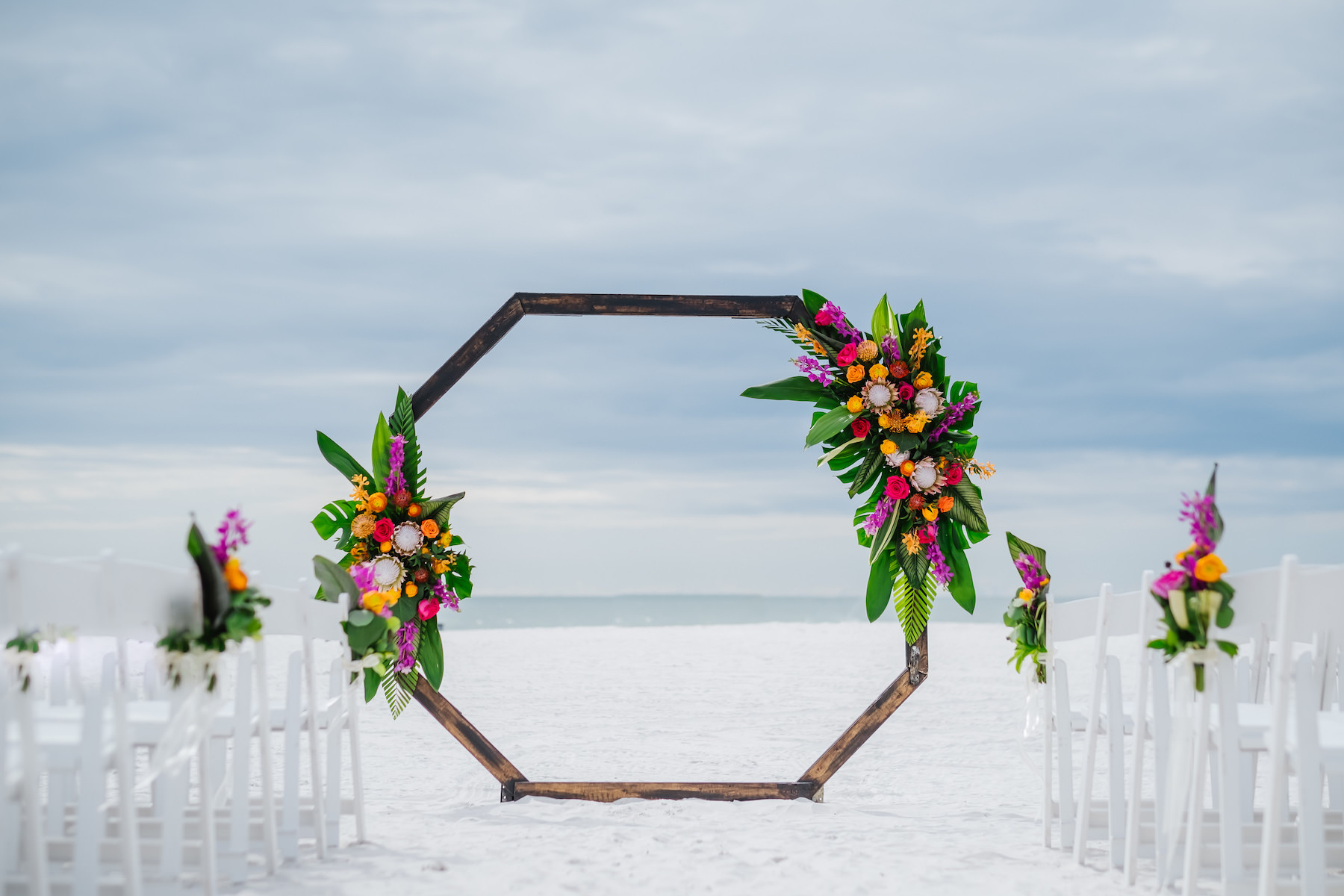 INSTAGRAM Clearwater Beach Waterfront Beachfront Wedding Reception Decor, Tropical Floral Arrangements, King Proteas, Palm Fronds, Monstera Palm Leaves, Orange, Pink, Purple and Yellow Floral Arrangements on Geometric Octagonal Ceremony Arch
