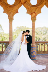 Bride in Classic Silhouette Open Back Wedding Dress and Full Length Veil and Groom First Look Wedding Portrait at Sarasota Waterfront Wedding Venue Ca d’Zan at The Ringling Museum