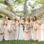 Romantic Bridal Party Portrait, Bridesmaids Wearing Mix and Match Blush Pink, Neutral and Champagne Dresses Holding Whimsical Orange and Pink Roses with Greenery Floral Bouquets, Bride in Lace and Illusion Neckline Fit and Flare Watters Wedding Dress | St. Petersburg Wedding Hair and Makeup Femme Akoi Beauty Studio | Tampa Bay Wedding Florist Bruce Wayne Florals