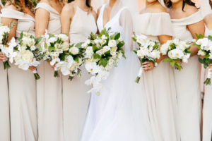 Classic Bride Holding White Orchids and Roses with Greenery Floral Bouquet and Bridesmaids in Neutral Cream Mix and Match Dresses Bridal Party Portrait