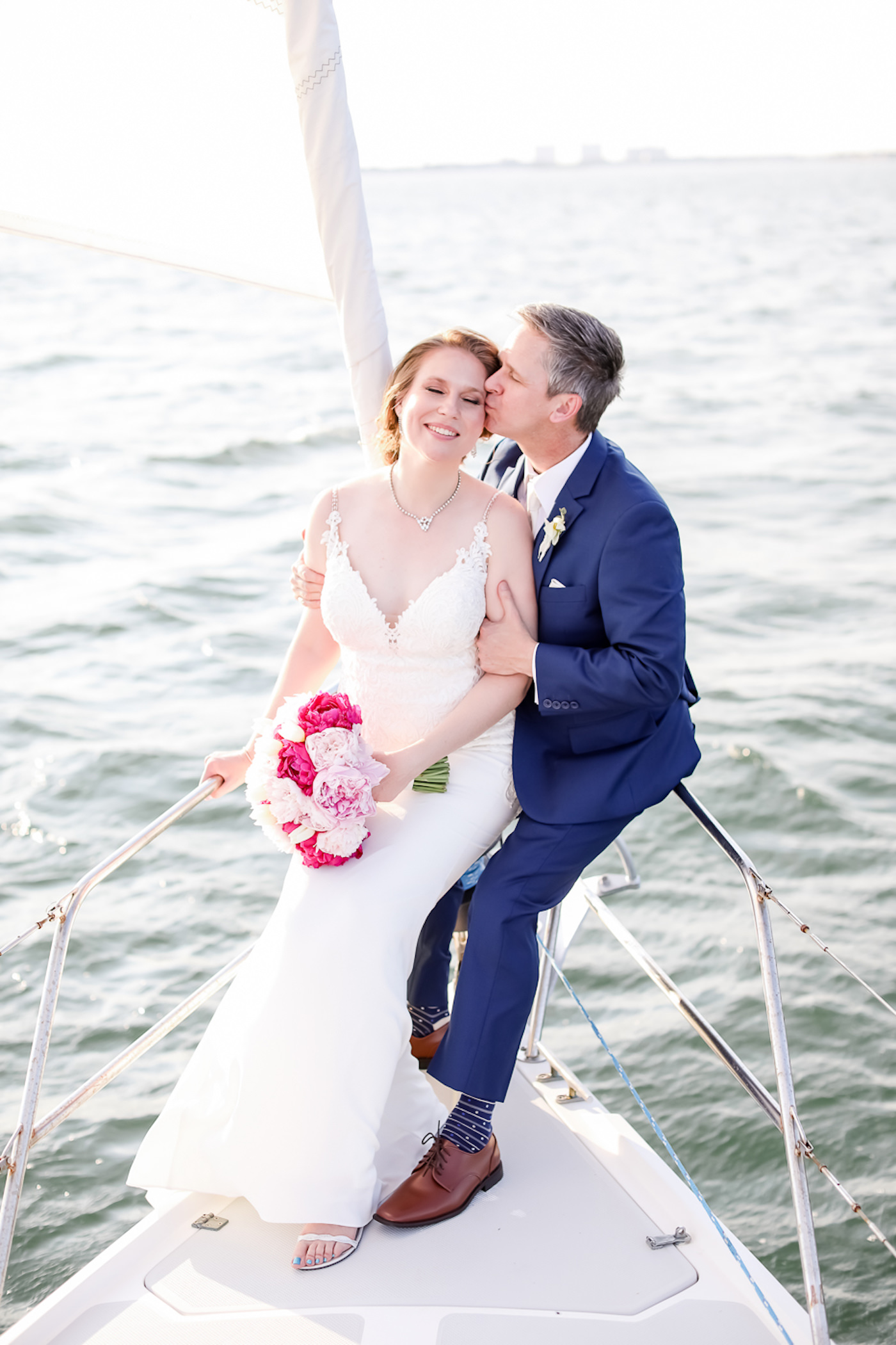 Romantic Bride and Groom on Yacht Wedding Portrait, Bride in Fitted Lace, V Neckline with Thin Spaghetti Straps Stella York Wedding Dress Hold Fuschia and Blush Pink Floral Bouquet, Groom in Blue Suit | Tampa Bay Wedding Photographer Lifelong Photography Studios | Wedding Hair and Makeup Michele Renee the Studio