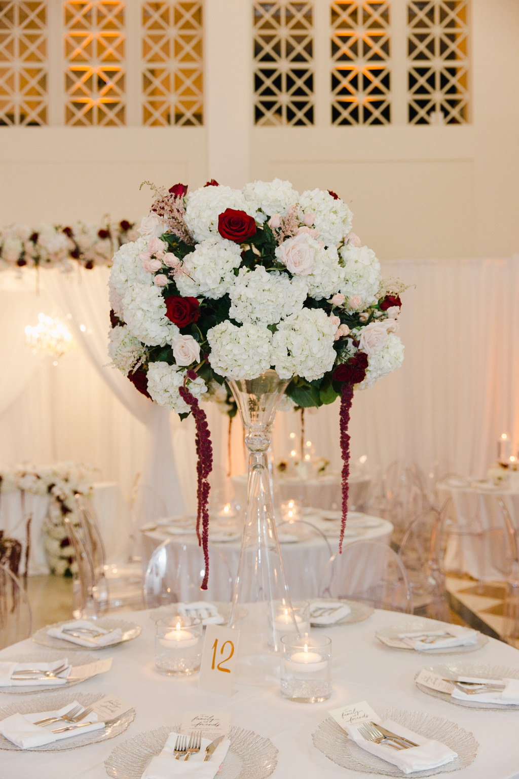 Elegant Wedding Reception Decor, Round Tables with White Tablecloths, Acrylic Ghost Chairs, Tall Glass Vase with White and Blush Pink Hydrangeas with Dark Red Hanging Amaranthus | Tampa Bay Wedding Venue The Vault | Wedding Florist and Rentals Gabro Event Services