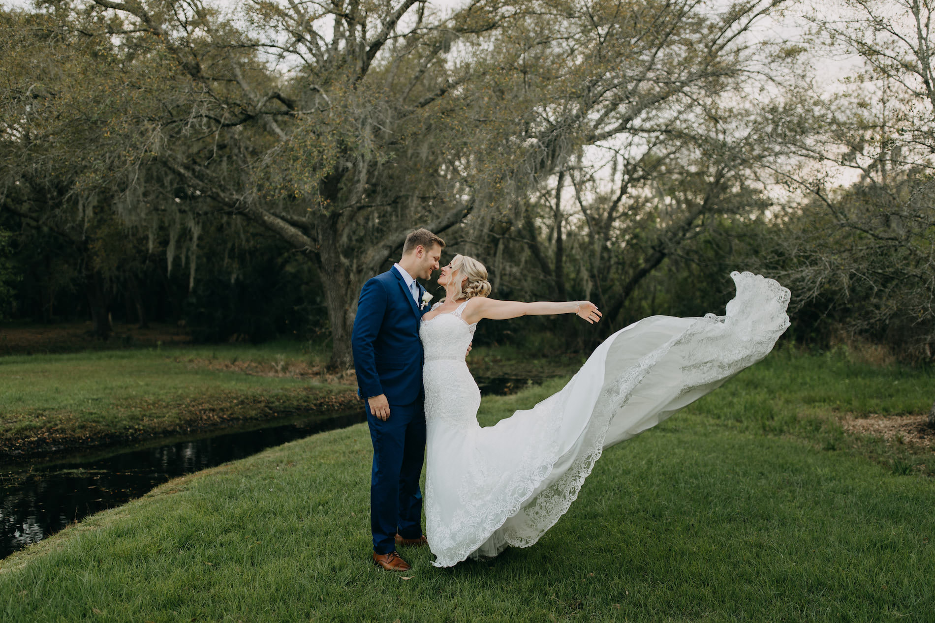 Fun Classic Bride and Groom Outdoor Wedding Portrait with Bride's Wedding Dress Train Blowing in the Wind