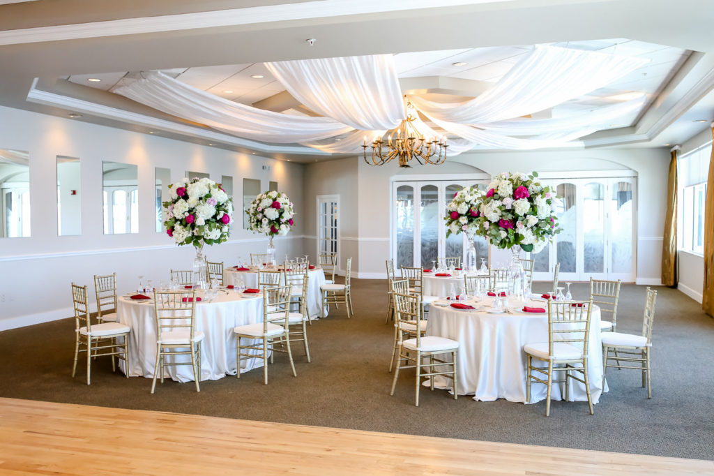 Tropical Romantic Ballroom Wedding Reception Decor, Round Tables with White Tablecloths, Maroon Linens, Gold Chiavari Chairs, Tall White Hydrangeas, Pink and Blush Roses with Greenery Floral Centerpieces, White Ceiling Draping, Gold Curtains | Tampa Bay Wedding Photographer Lifelong Photography Studios | St. Pete Waterfront Wedding Venue Isla Del Sol Yacht and Country Club | Wedding Rentals a Chair Affair, Over the Top Linens