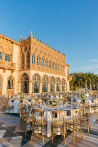 Classic Elegant Waterfront Wedding Reception Decor, Long Feasting Tables and Round Tables with White Tablecloths, Navy Blue Linens, Gold Chairs and Low Floral Centerpieces | Sarasota Historic Wedding Venue Ca d’Zan at The Ringling Museum | Tampa Bay Wedding Planner NK Productions
