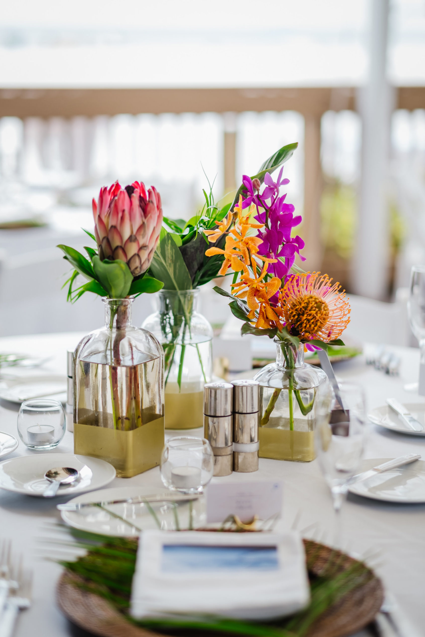 Tropical Wedding Reception Decor, Small Gold and Clear Vases with King Protea, Orange and Purple Flowers and Palm Leaves Centerpieces